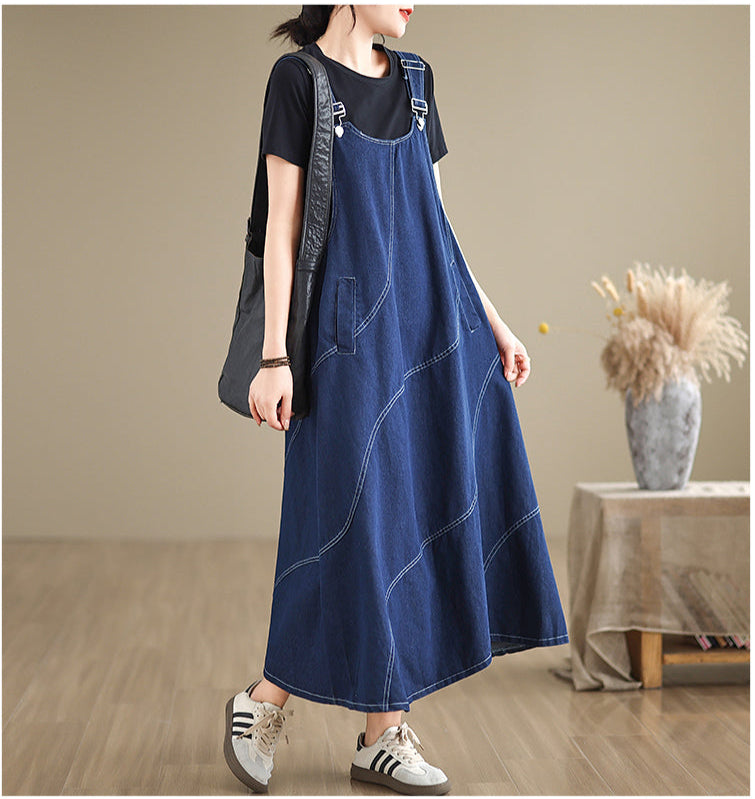 Woman wearing a blue denim dress over a black t-shirt in a minimalistic room.