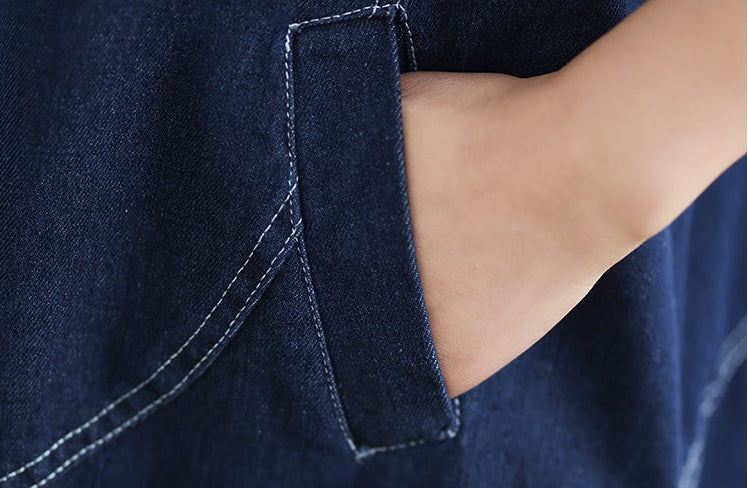 Close-up of a person wearing a navy blue denim shirt with a pocket detail.