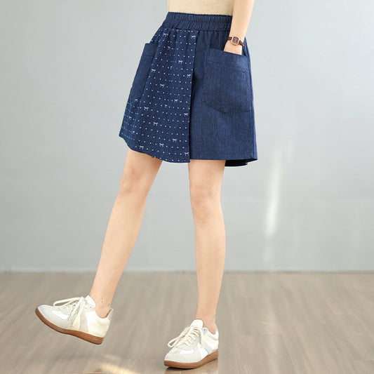 Person wearing a blue denim skirt with white polka dots on a plain background