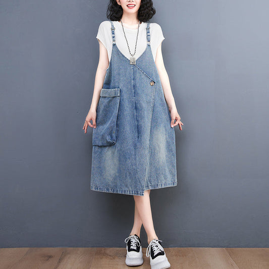 Person wearing a denim pinafore dress with a plain background