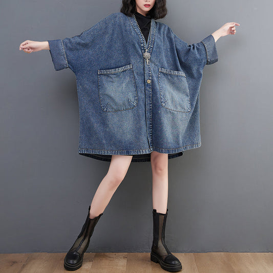 Person wearing a blue denim dress with a plain background