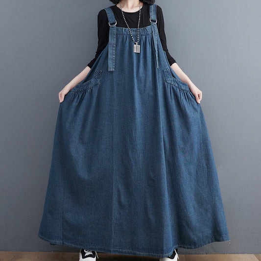 Person wearing a long denim dress against a gray background