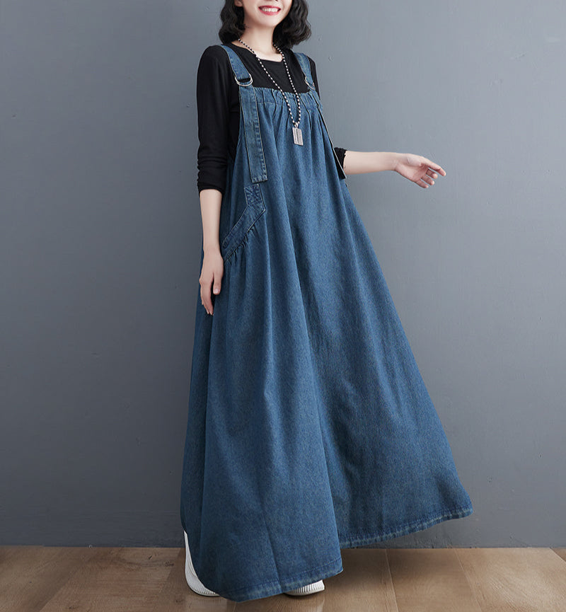 Person wearing a long denim dress against a gray background