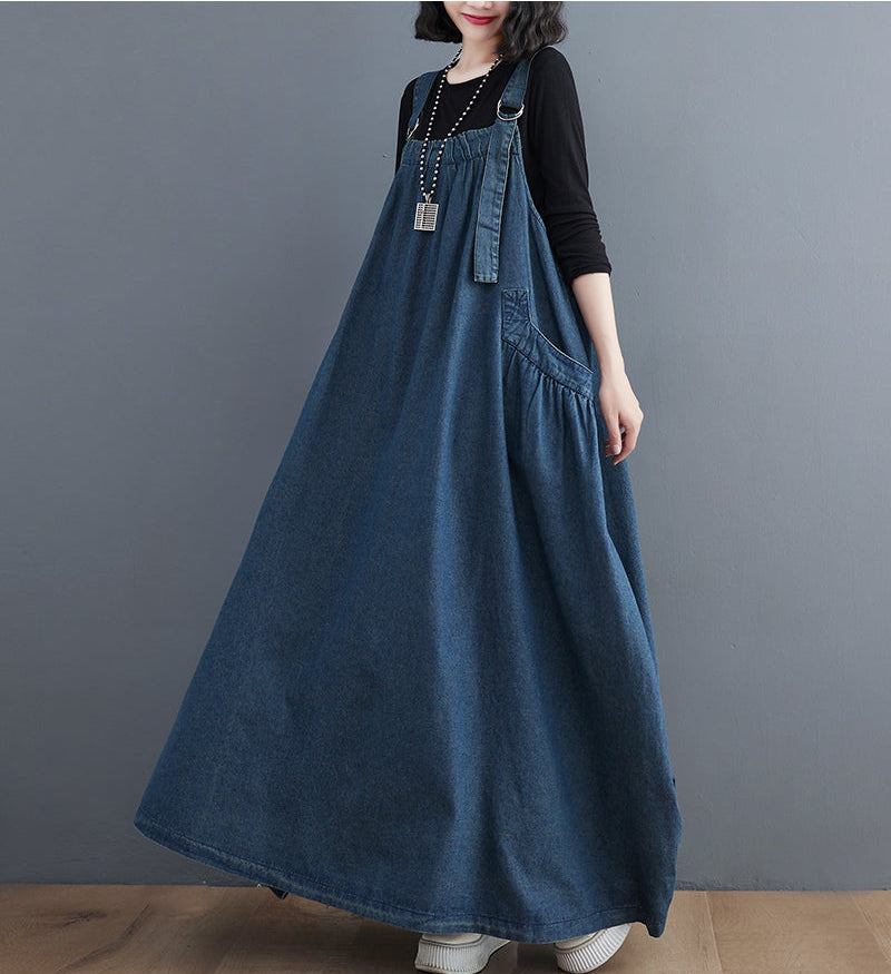 Person wearing a long denim dress against a gray background