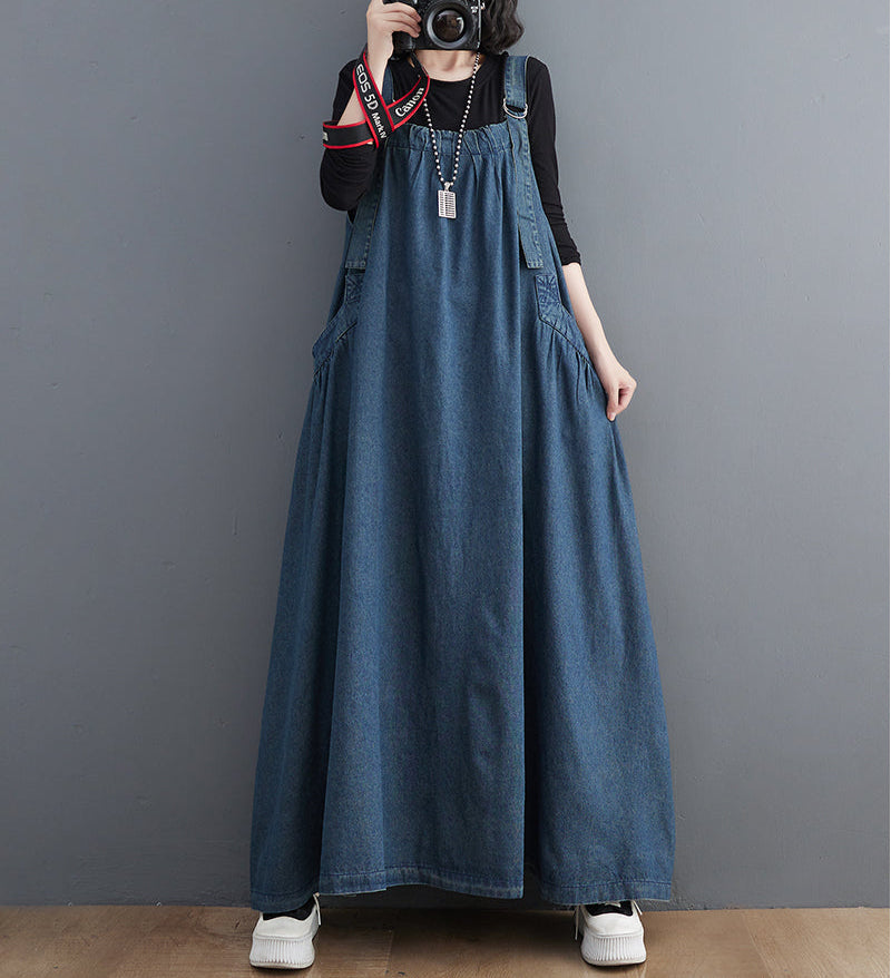 Person wearing a long blue denim dress against a gray background