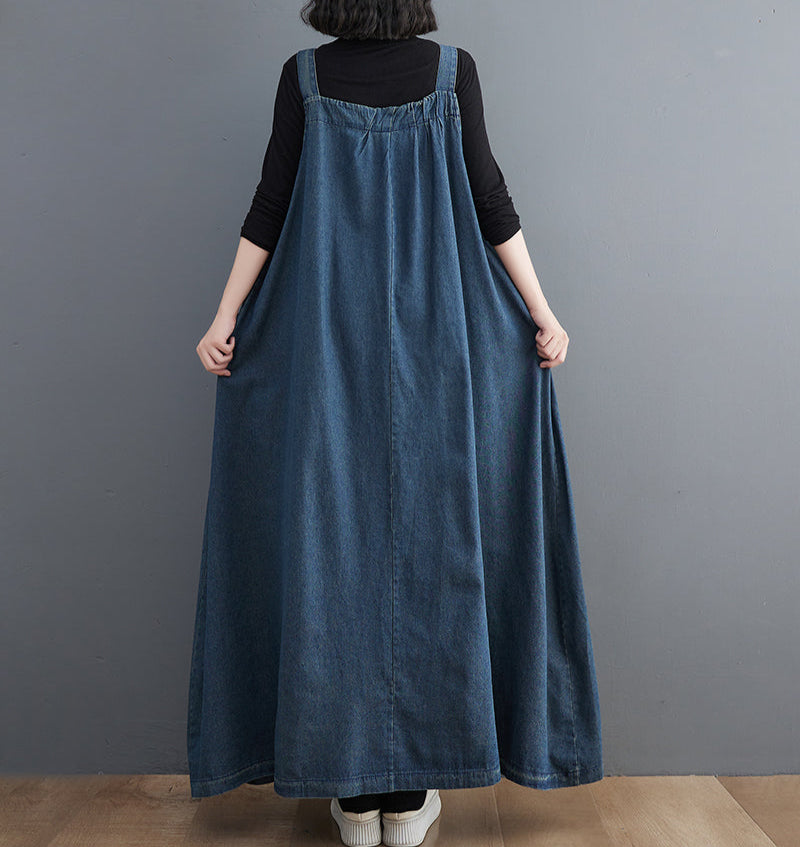 Person wearing a long denim dress against a gray background