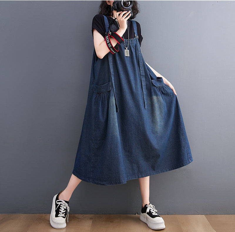 Person wearing a blue denim dress against a gray background