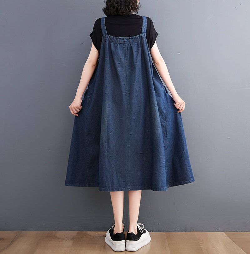 Person wearing a blue denim dress against a gray background