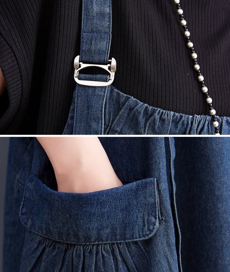 Close-up of a blue denim apron with a buckle and a pocket, worn over a dark top.