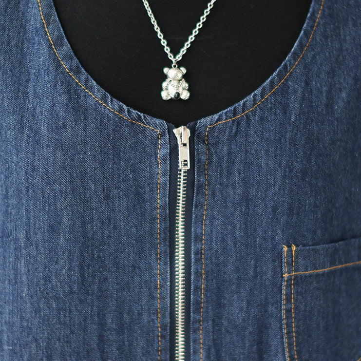 Close-up of a blue denim jacket with a teddy bear pendant necklace.