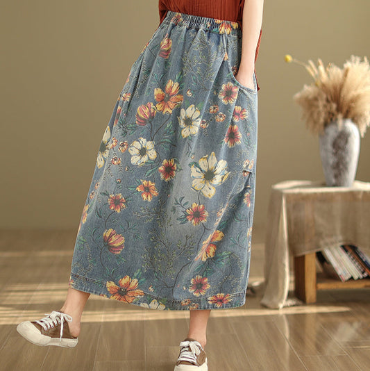 Person wearing a floral denim skirt in a room with a wooden floor and a small table with a vase.