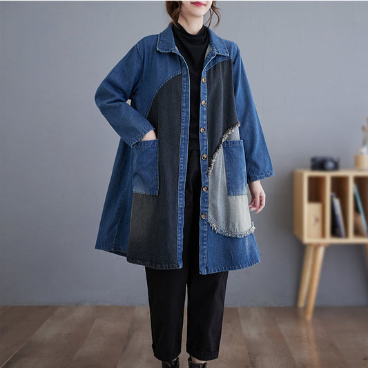 Person wearing a blue denim coat with patchwork design in a minimalistic room.